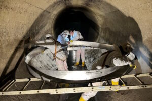Personen in Schutzkleidung beim Einbau einer DN 3000 Manschette in einen undichten Kanal
