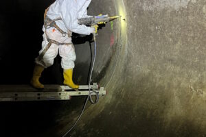 Person in Schutzkleidung bei der Kanalsanierung