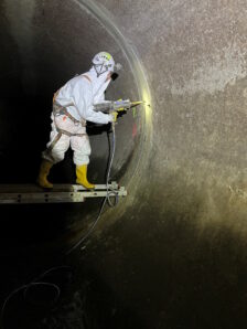 Person in Schutzkleidung bei der Kanalsanierung